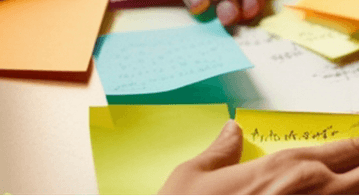 Hands sorting sticky notes on a table